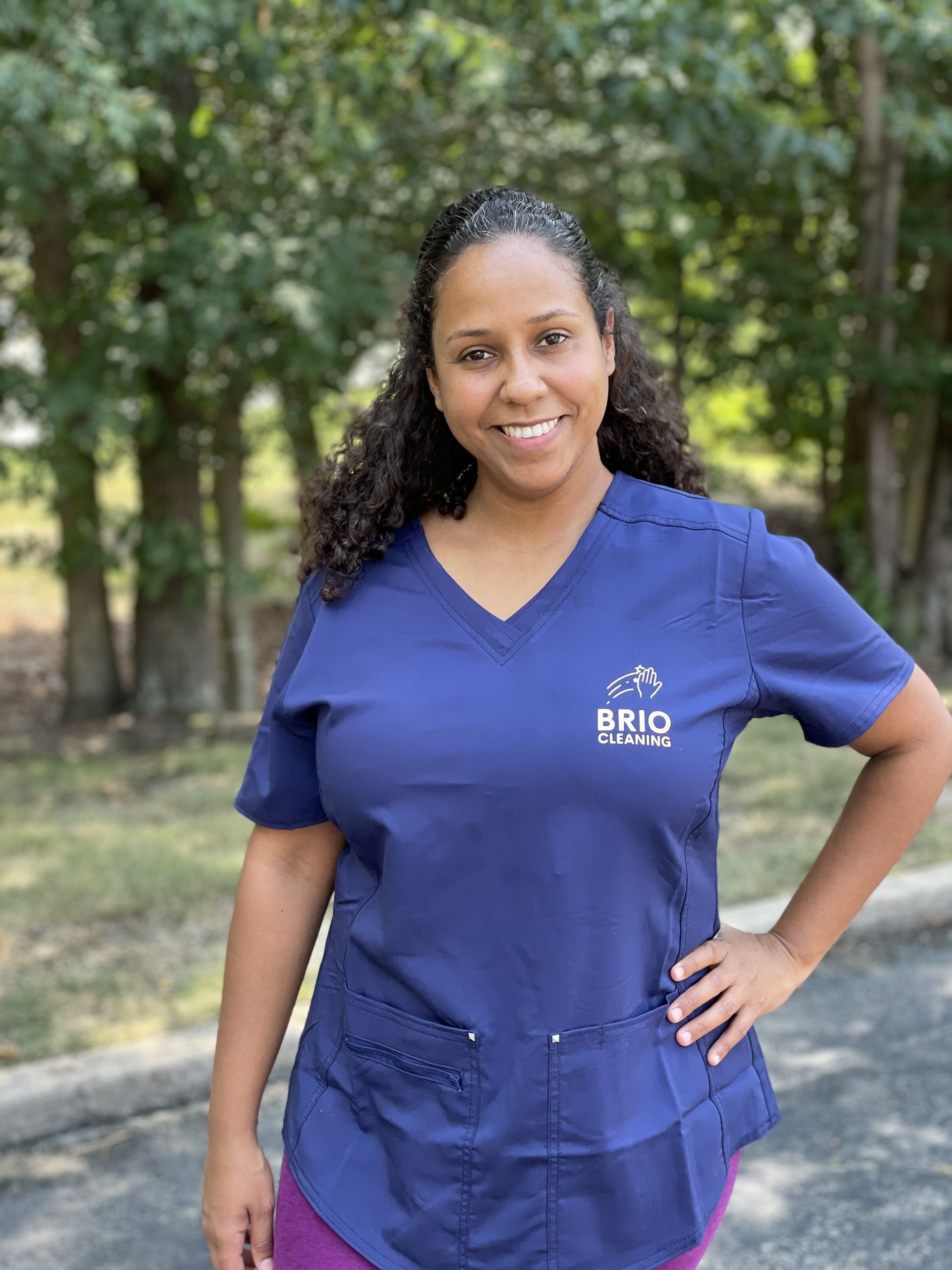 a woman wearing a blue scrub top is standing with her hands on her hips .