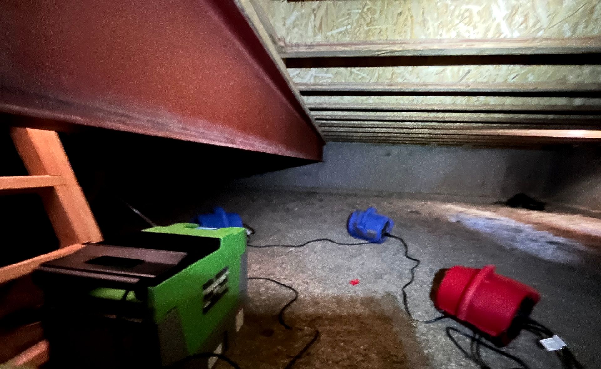 A green box is sitting on the floor next to a red vacuum cleaner.