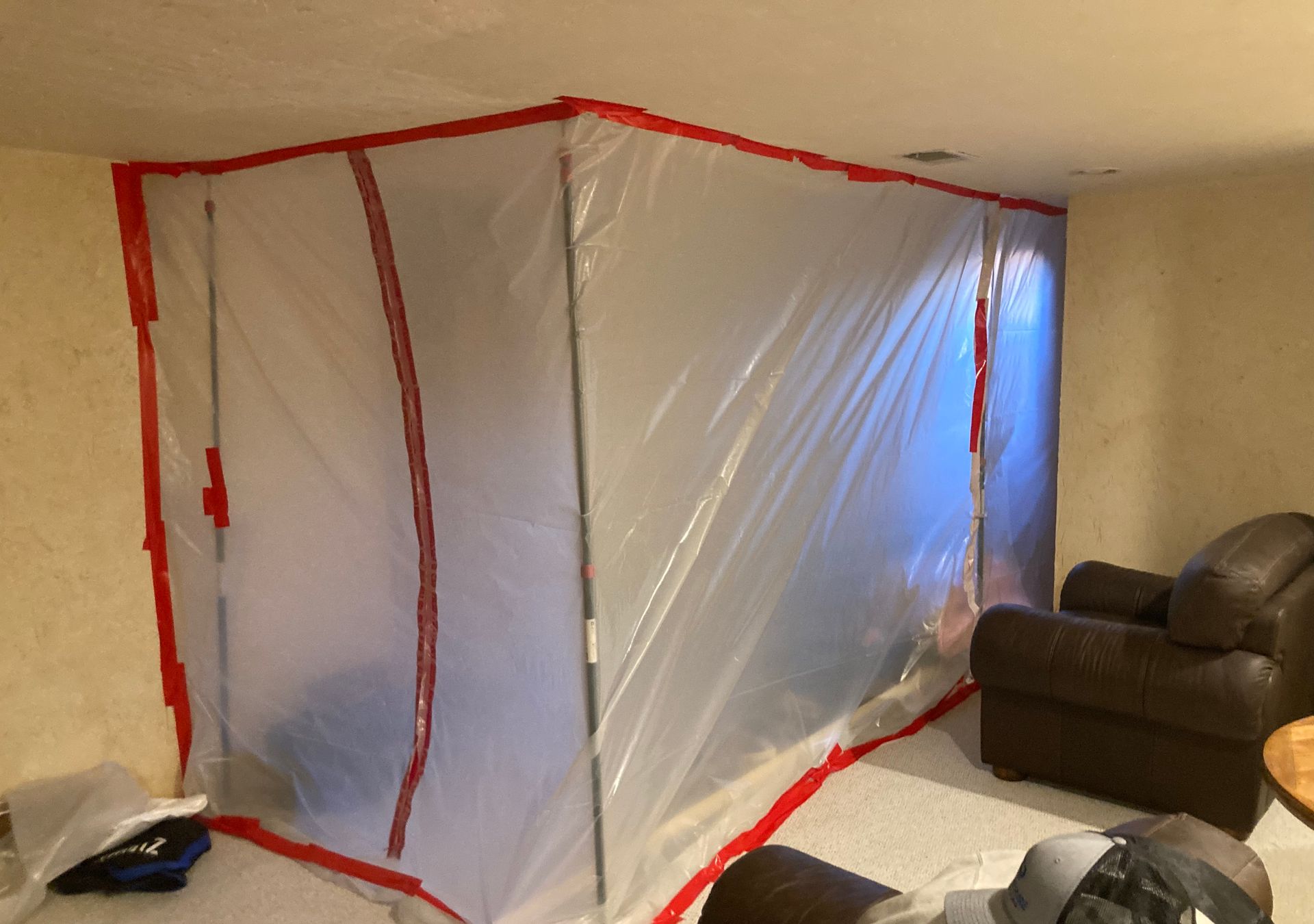 A living room with a chair and a white tarp on the wall.