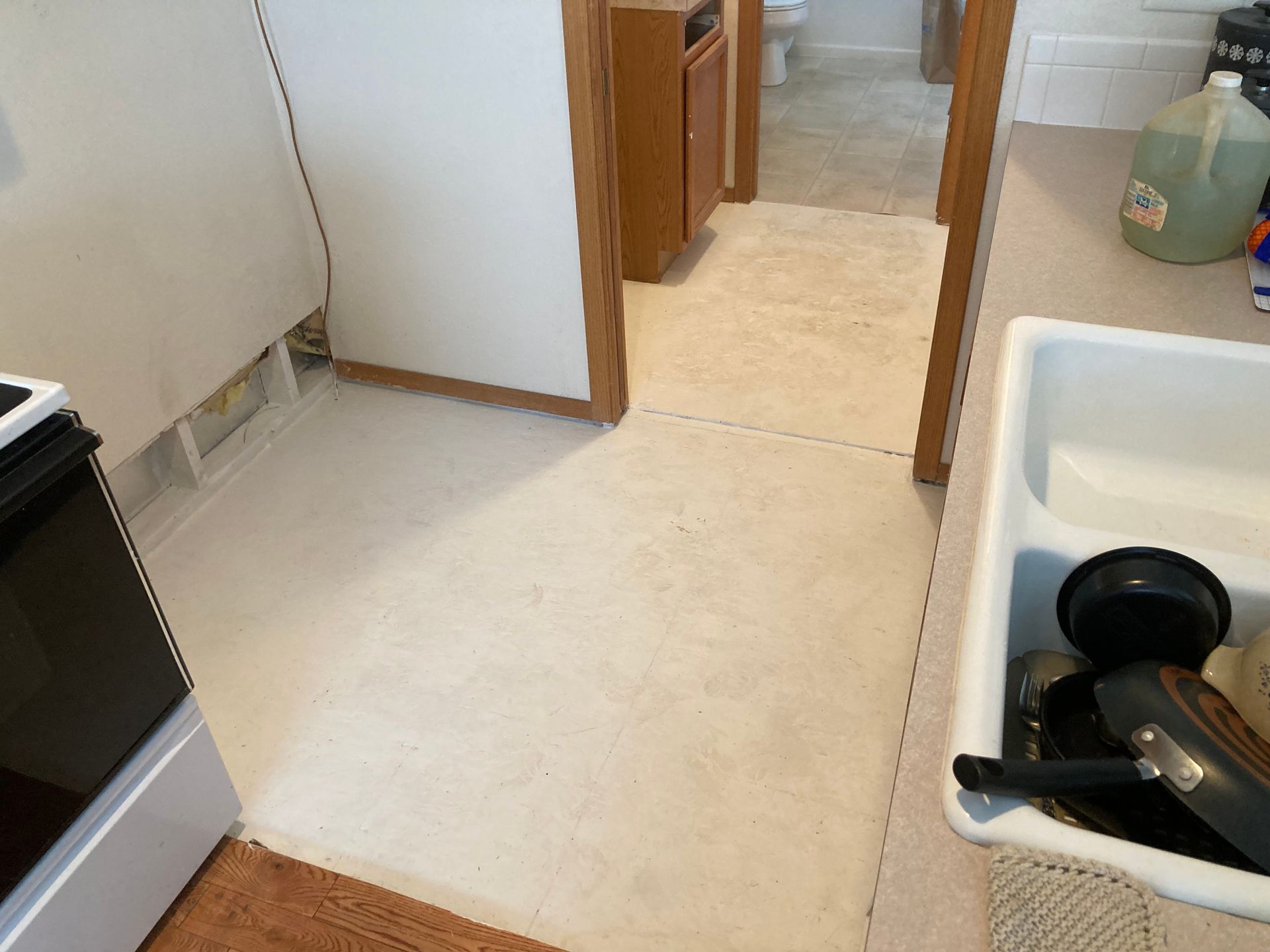 A kitchen with a sink and a stove and a doorway leading to a bathroom
