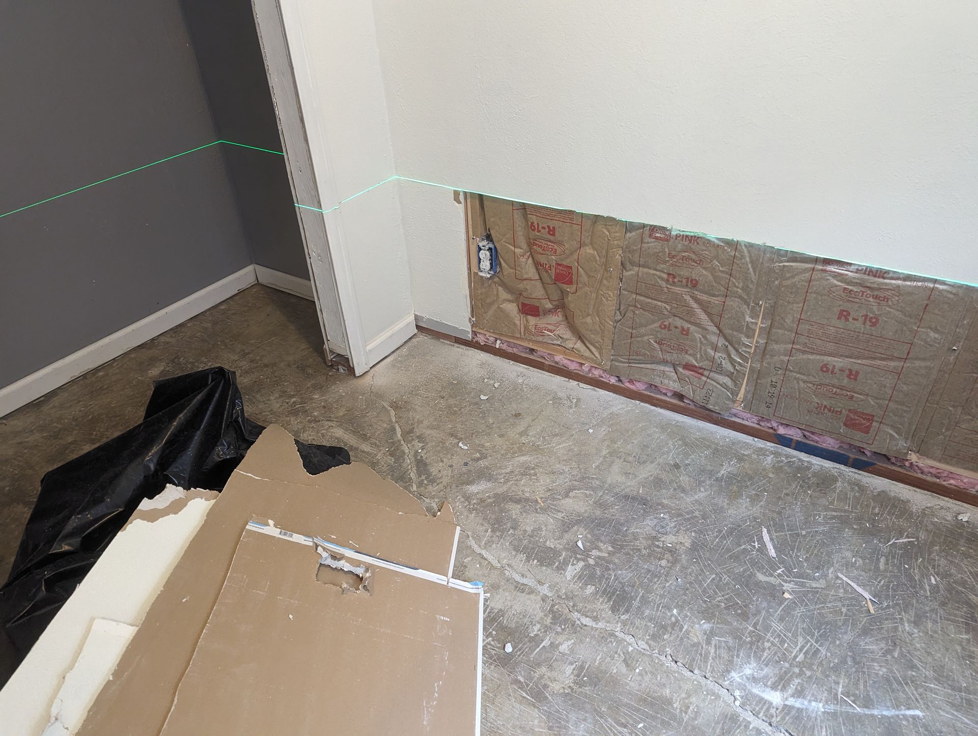 A green laser is being used to measure a wall in a room.