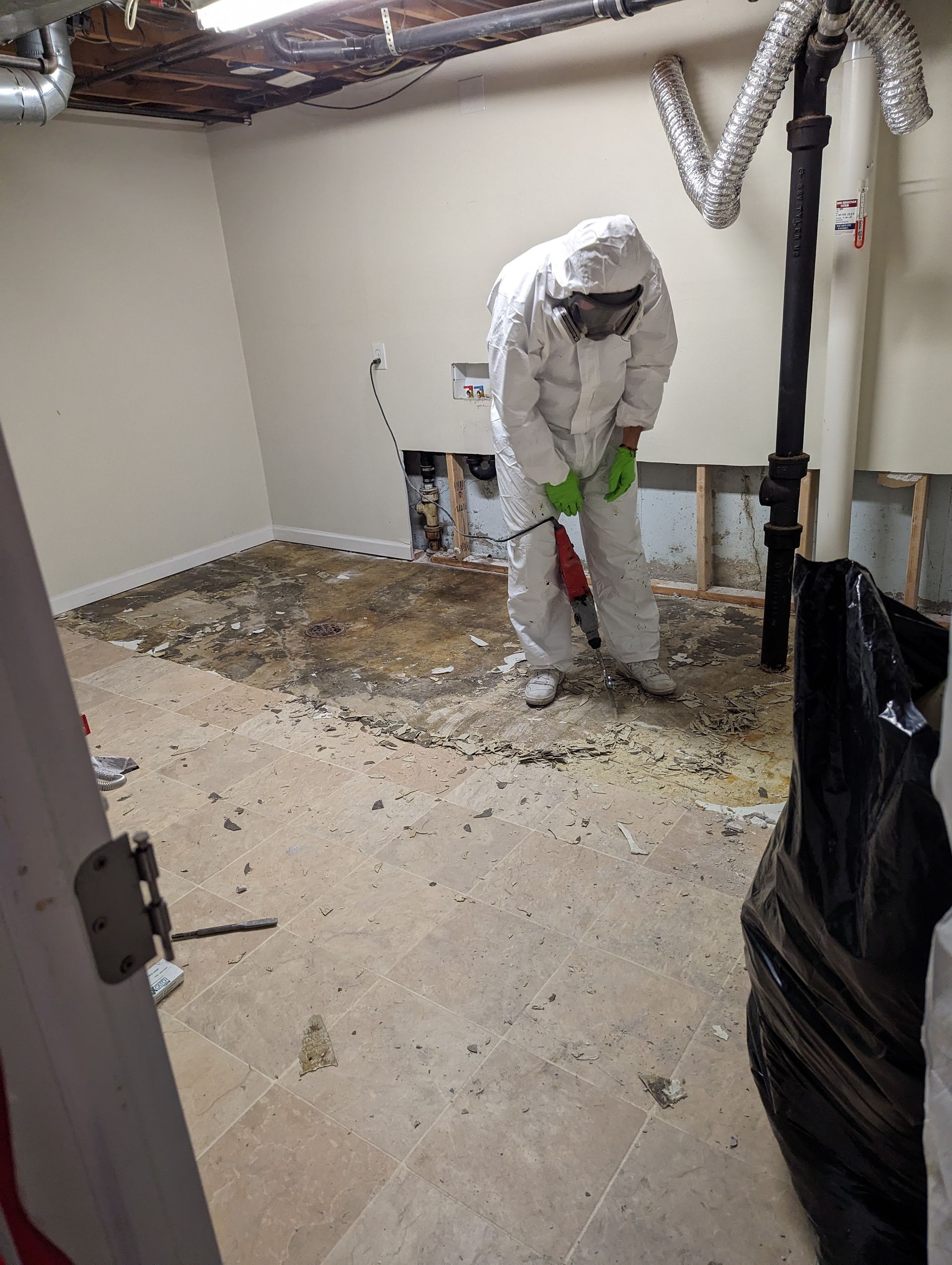 A man in a protective suit is working in a basement.