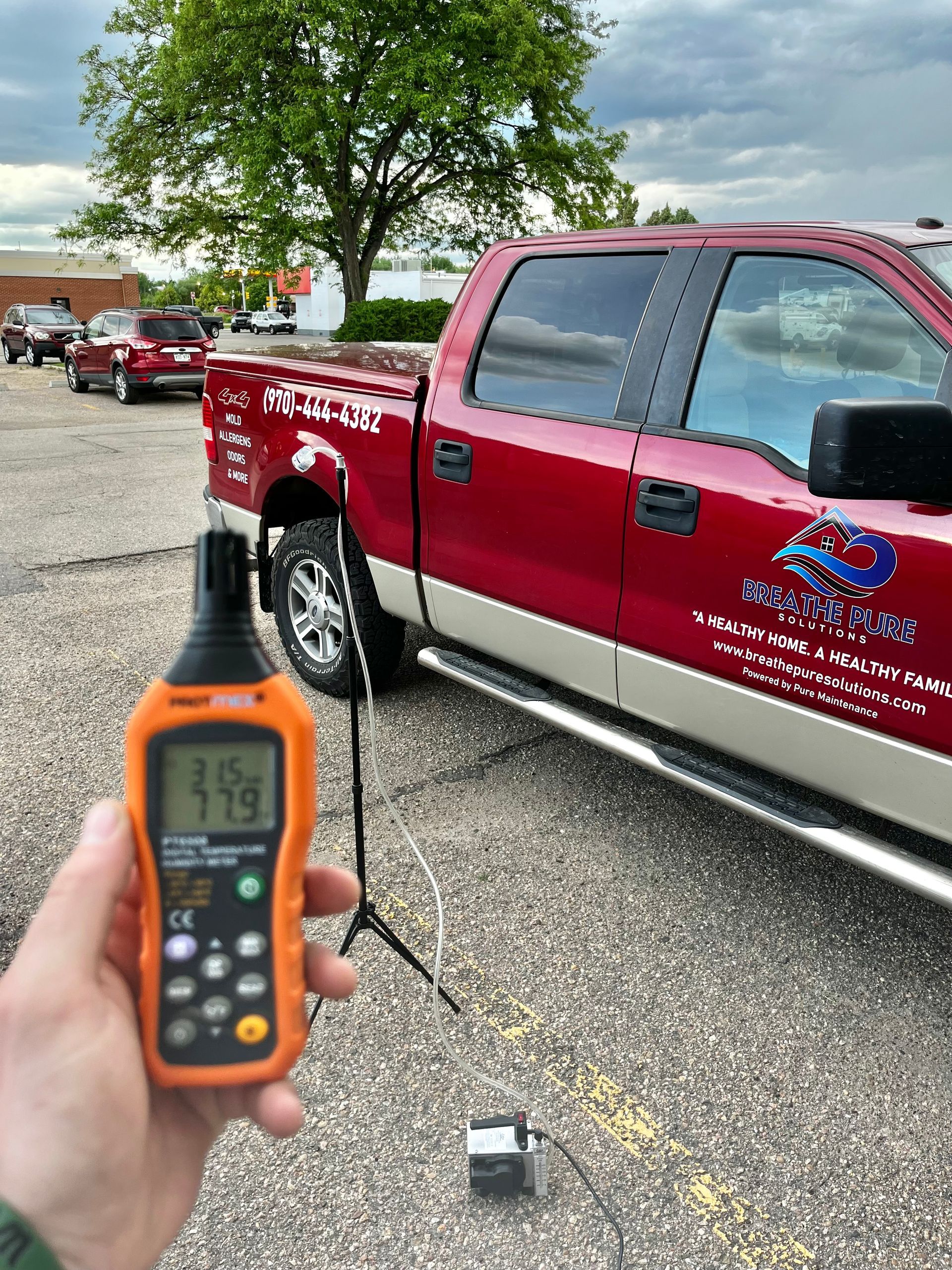 A person is holding a thermometer in front of a red truck