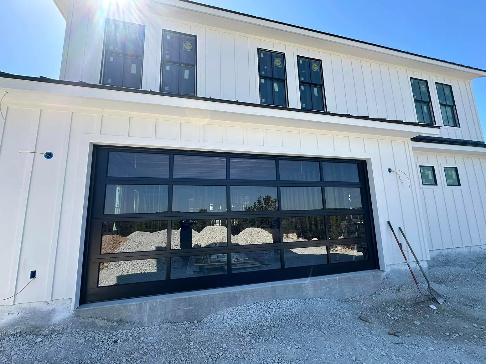 A white house with a black garage door and windows.