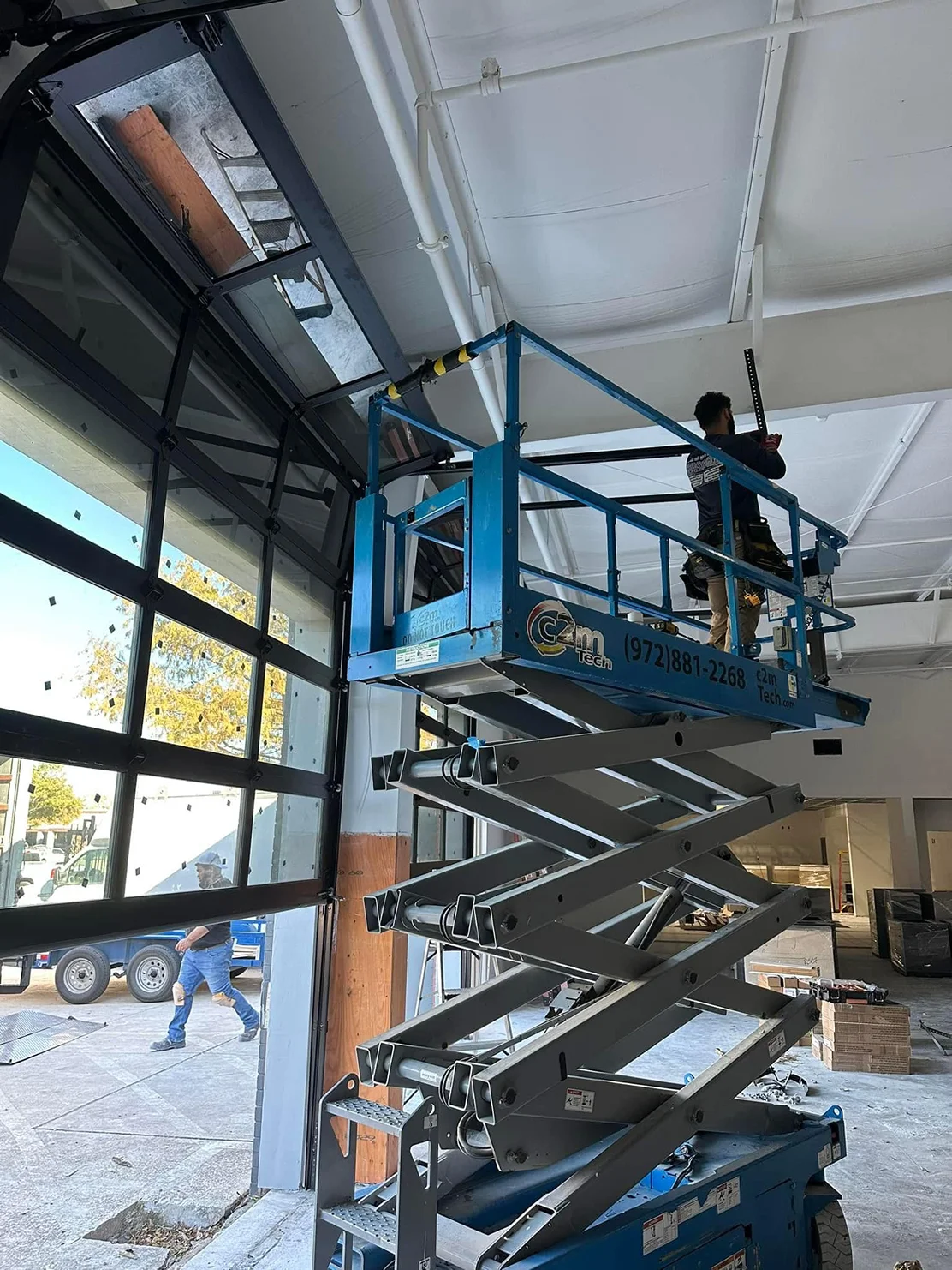 A man is standing on a scissor lift in a building.