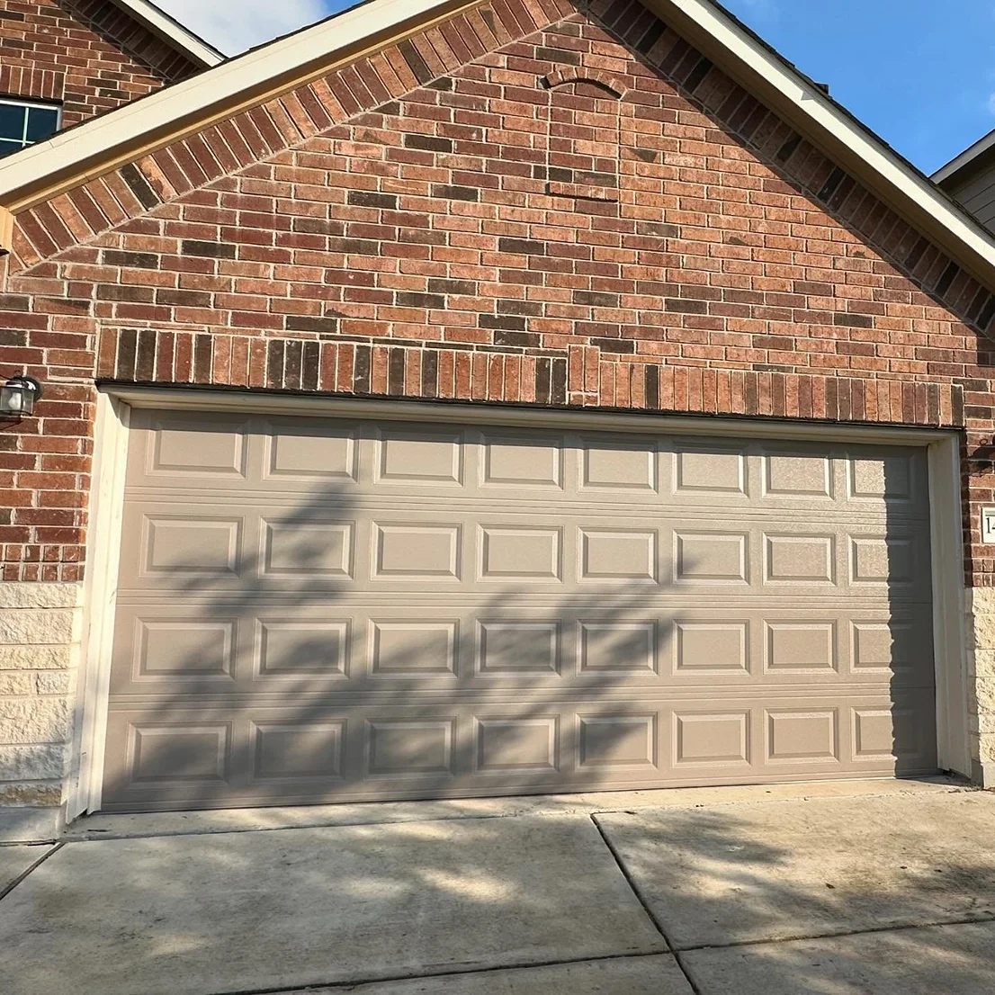 A brick house with a tan garage door