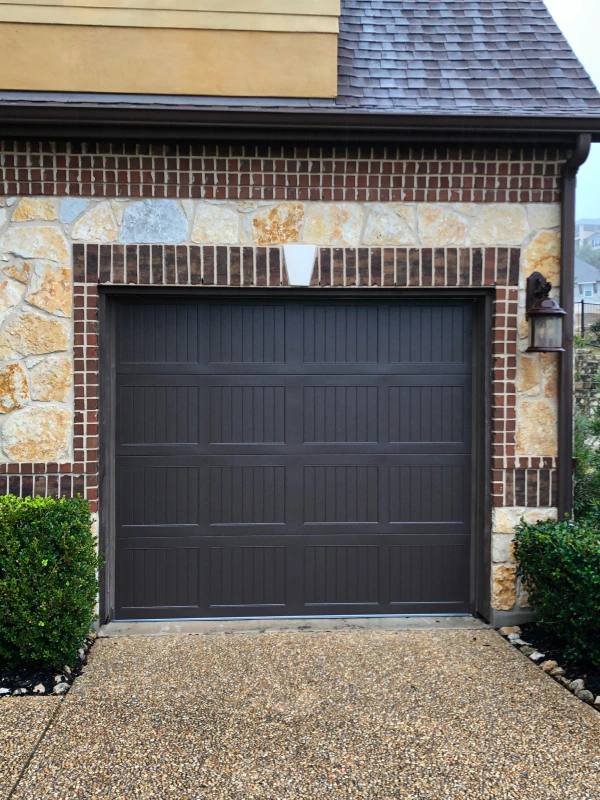 A brown garage door is on a brick building