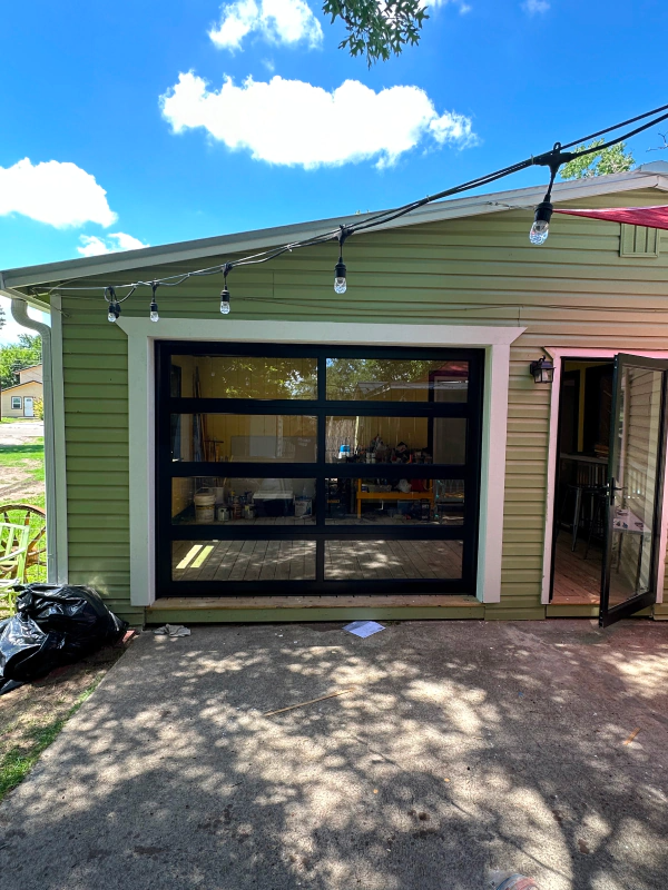 A green house with a black garage door