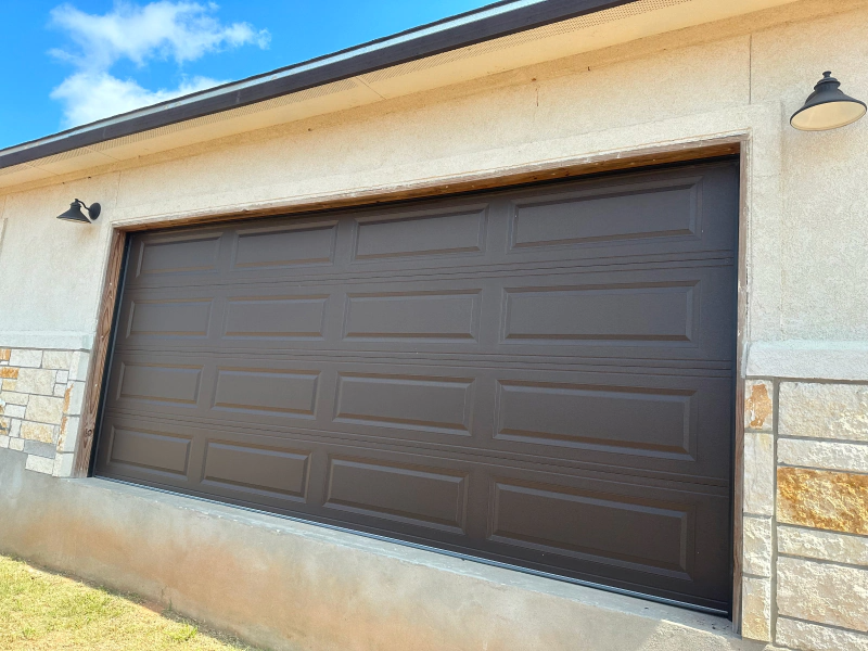 A brown garage door is on the side of a house.
