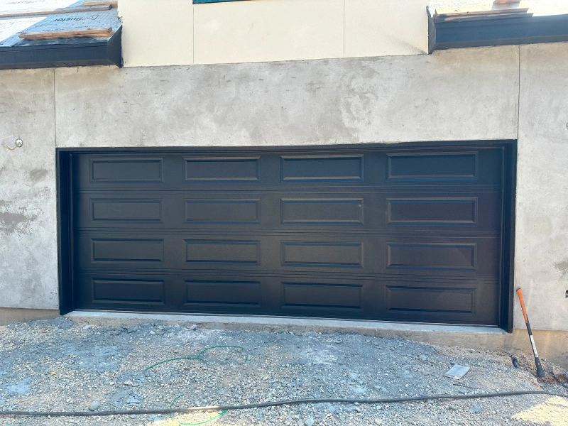 A black garage door is sitting on the side of a building.