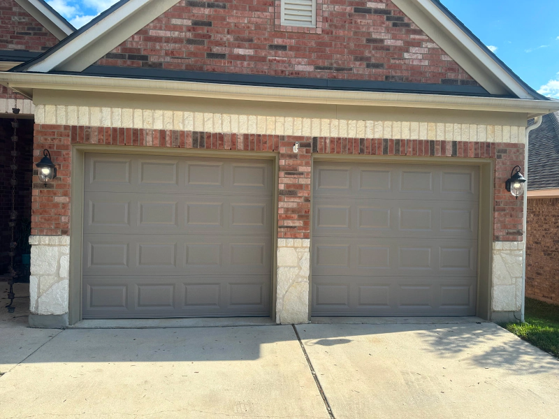 A brick house with two garage doors in front of it