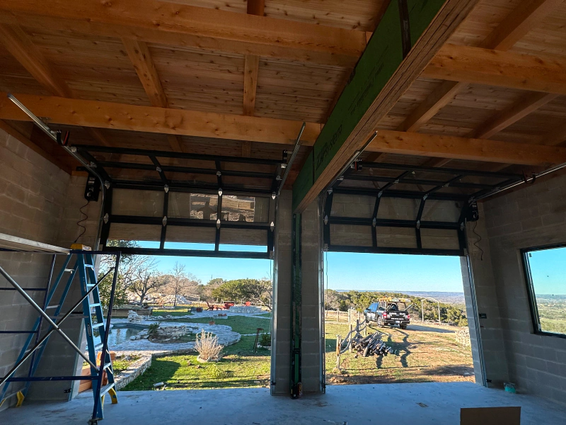 A garage door is open to a field with a tractor in the background.
