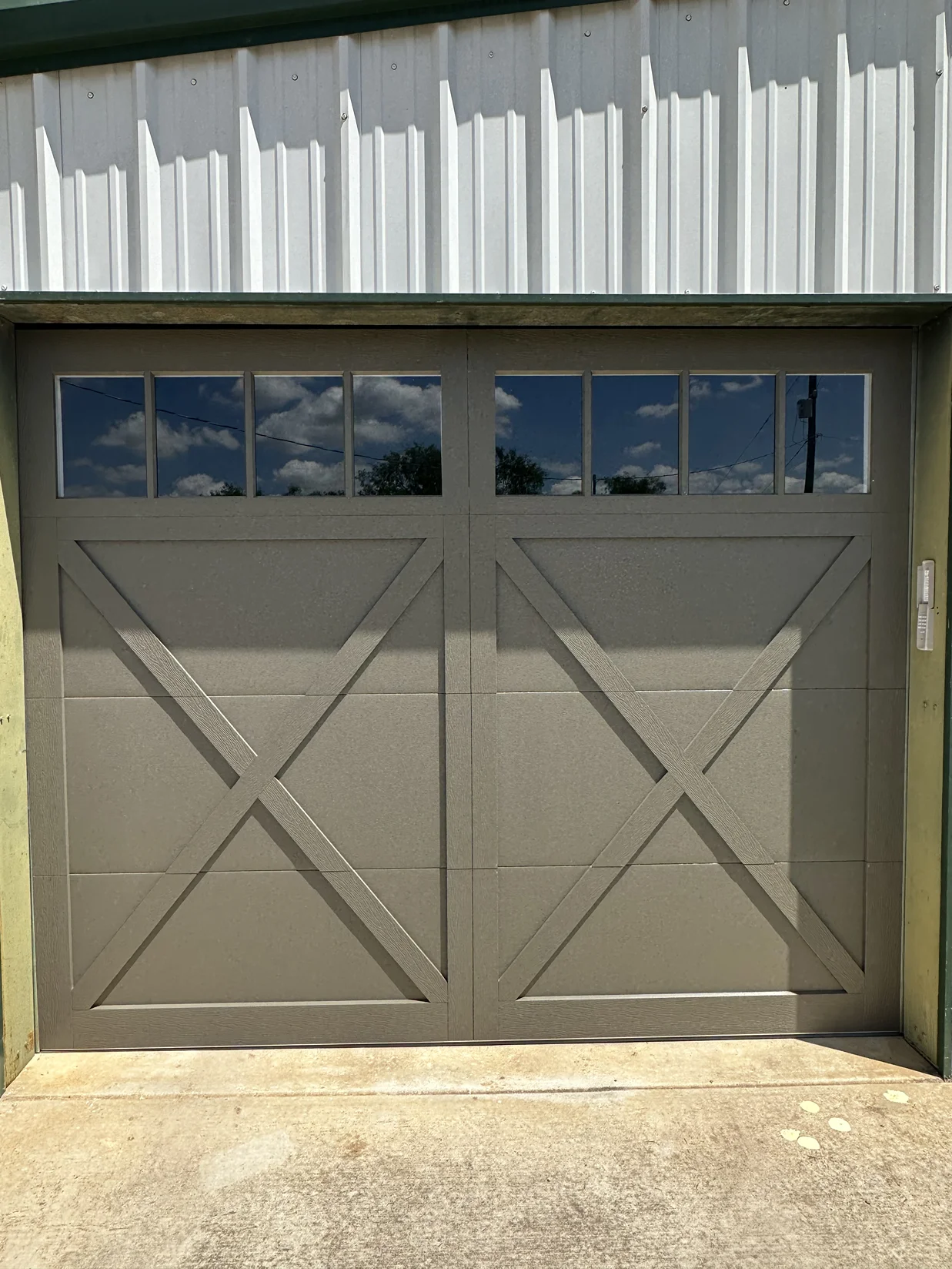 A garage door with a cross on it is sitting in front of a building.