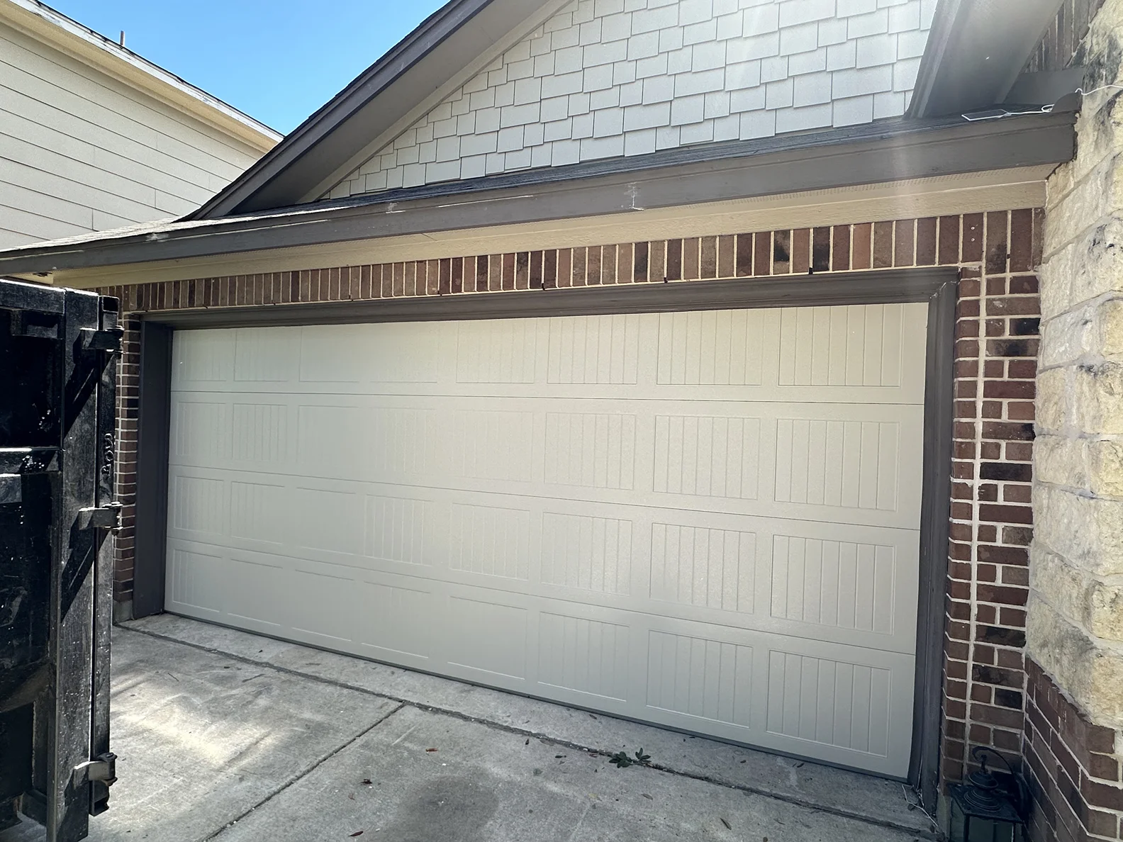 A white garage door is sitting in front of a brick house.