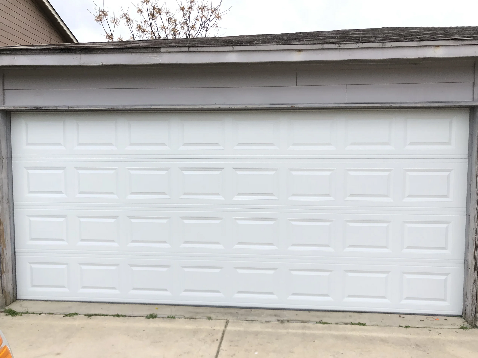 A white garage door is sitting on the side of a house.