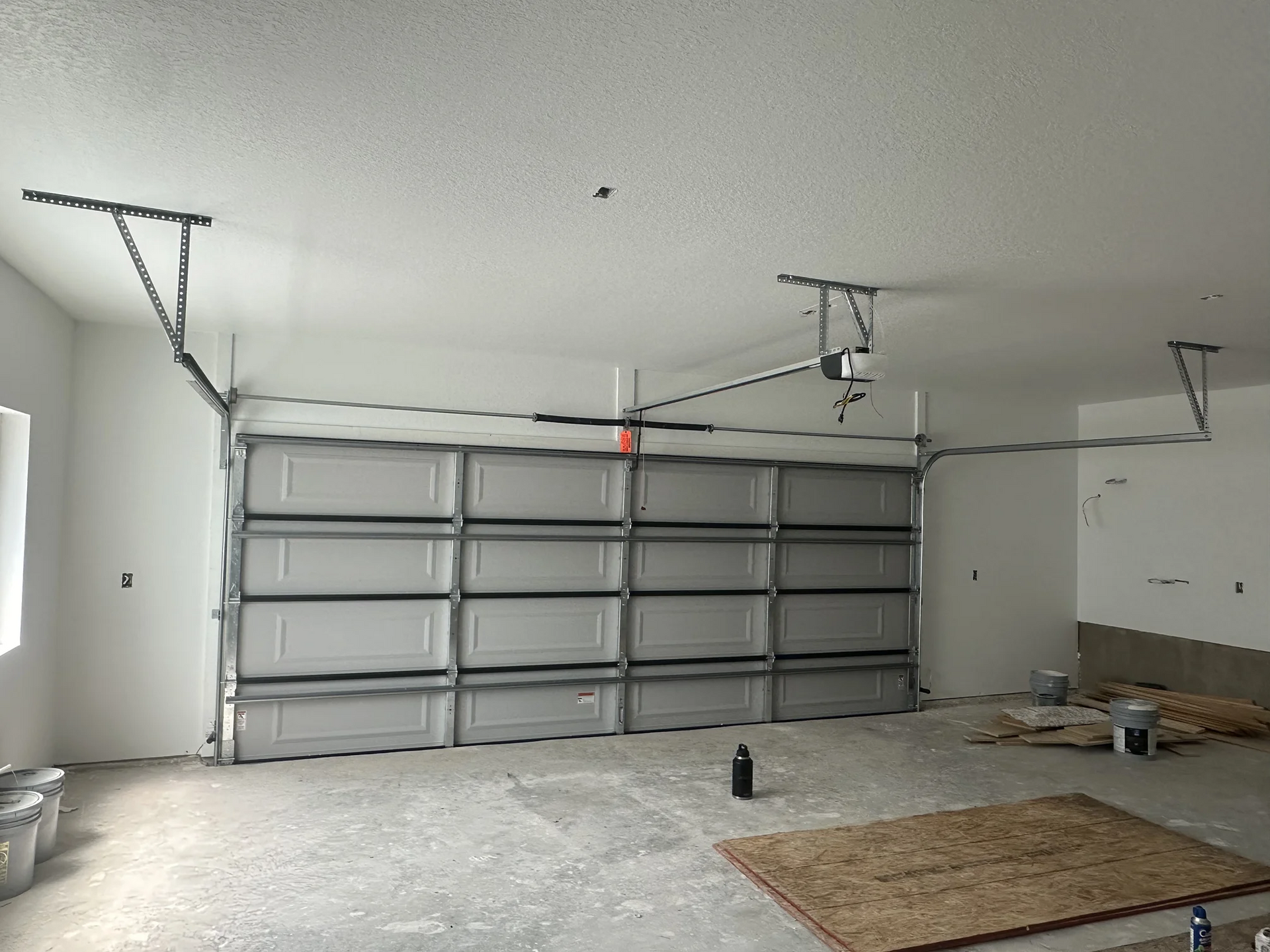 A garage with a garage door open and a rug on the floor.