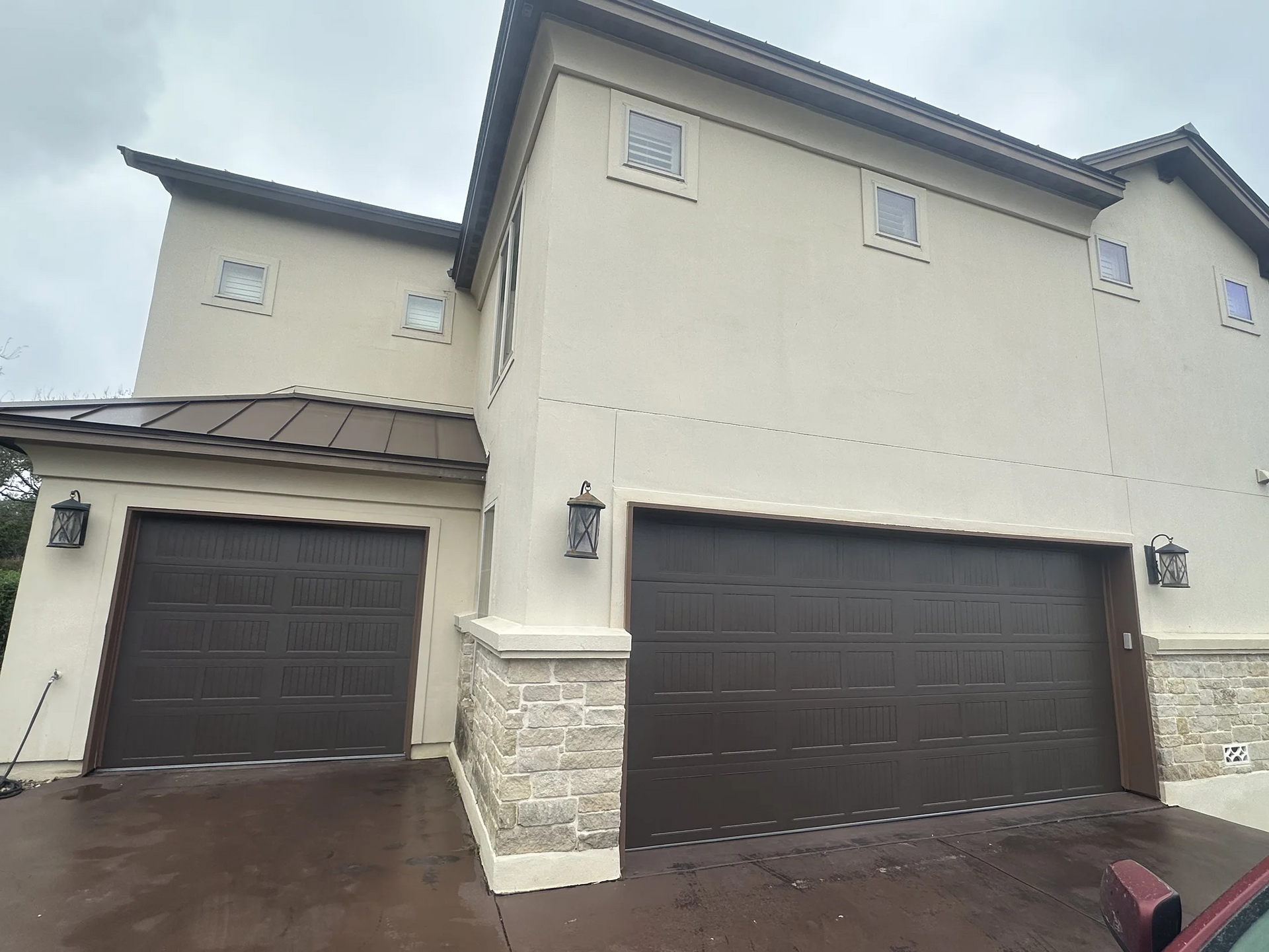 A large house with two garage doors and a car parked in front of it.