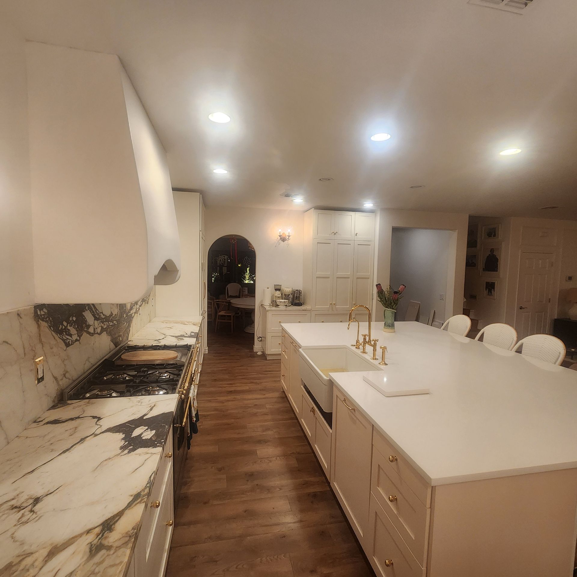 Spacious kitchen with white cabinets, marble countertops, and a large island with seating.