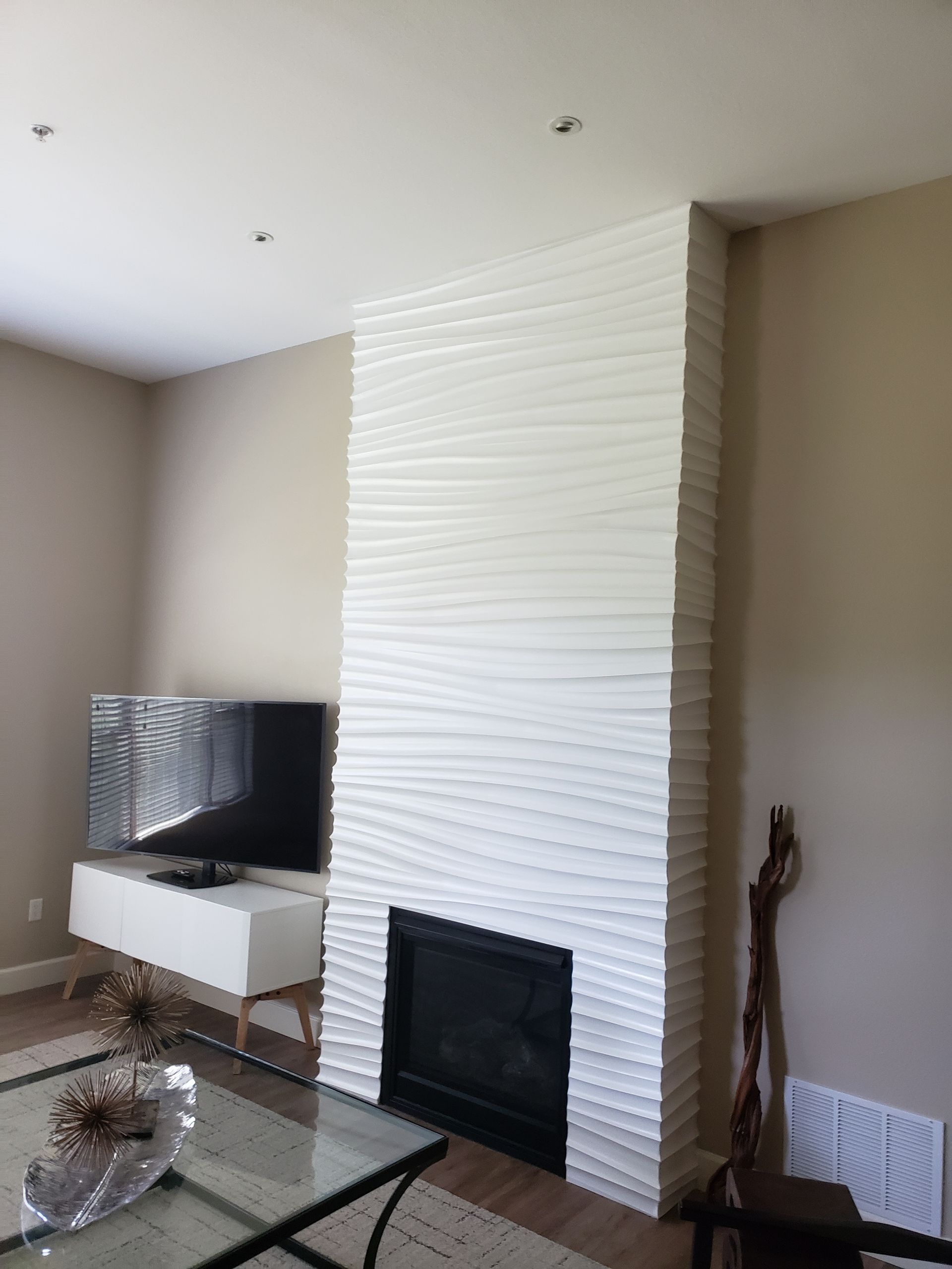 Living room with white textured fireplace, TV on white stand, and beige walls.
