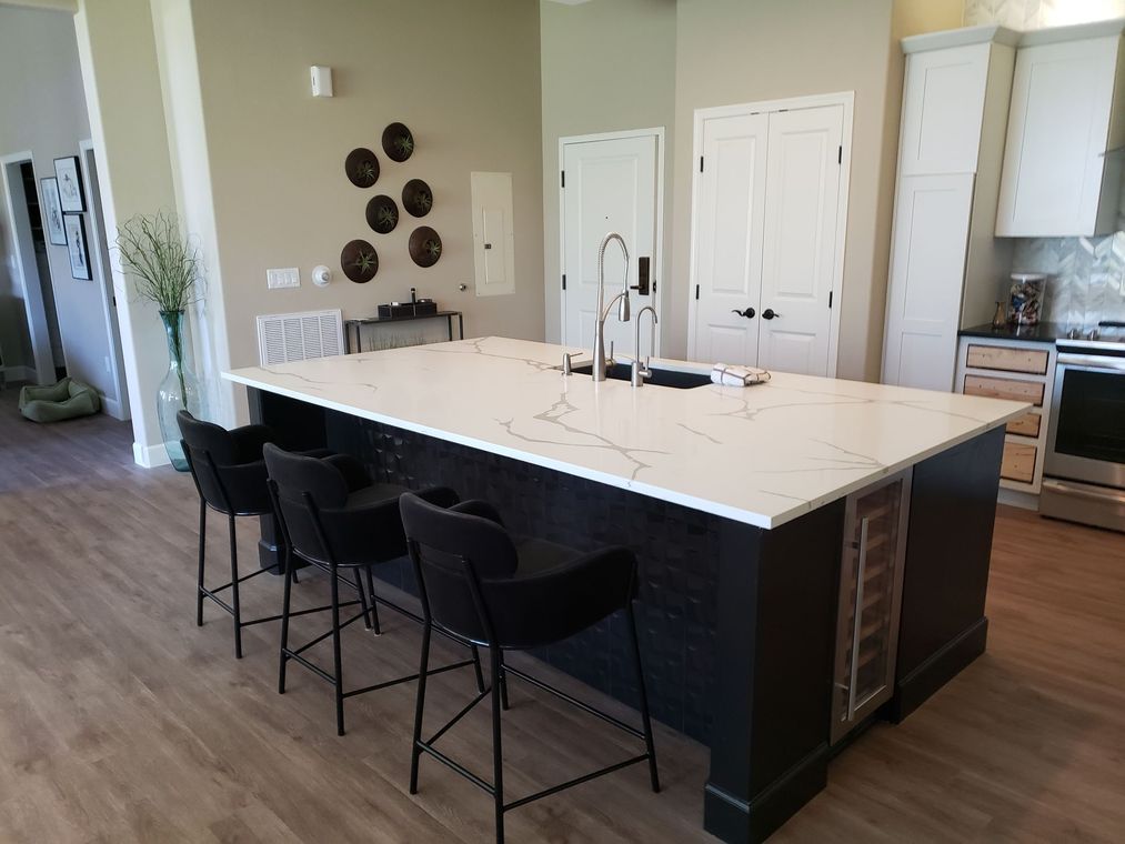Kitchen island with black stools, white countertop, and black cabinets.