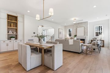 Bright open-concept dining and living room with light wood floors, white walls, and beige furnishings
