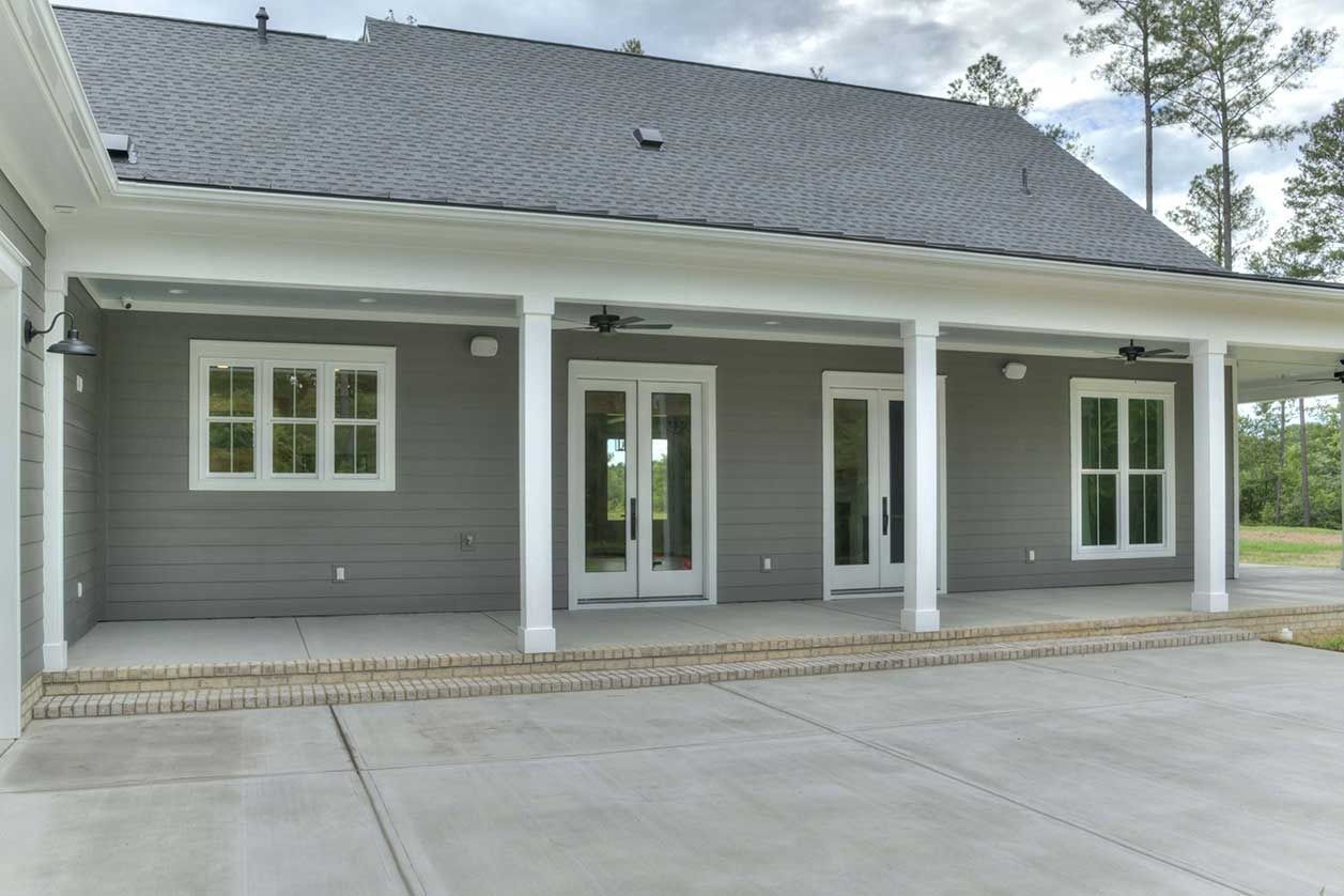 Gray house with white trim and covered front porch, centered double doors, and paved driveway