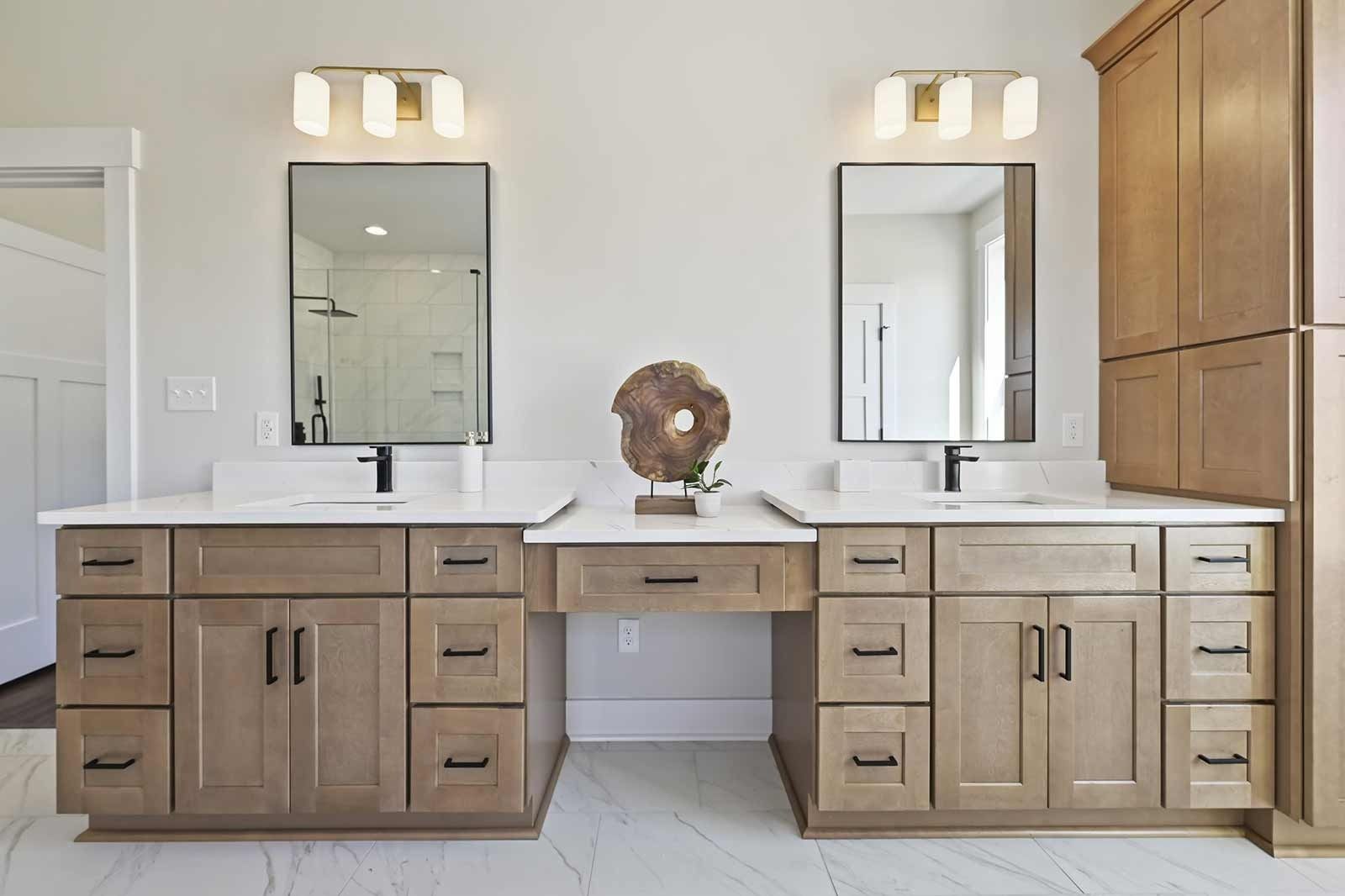 Double vanity bathroom with wood cabinets, white counters, mirrors, and wall sconces.