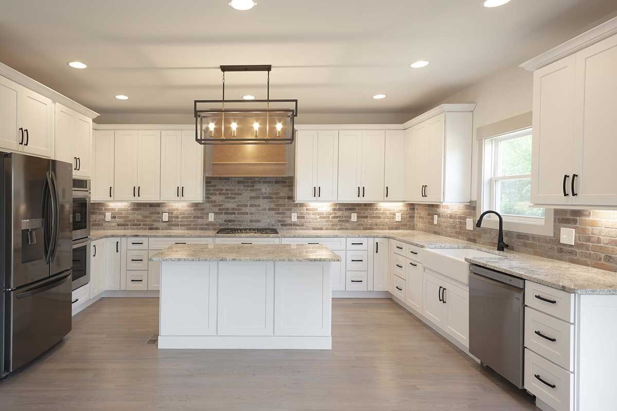 Spacious modern kitchen with white cabinets, stainless steel appliances, and a large central island