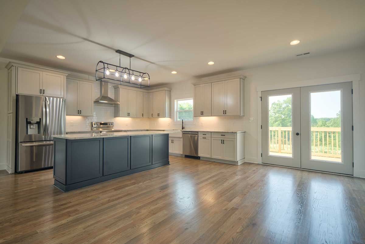 Bright modern kitchen and open dining area with blue island, stainless appliances, and French doors to outdoors