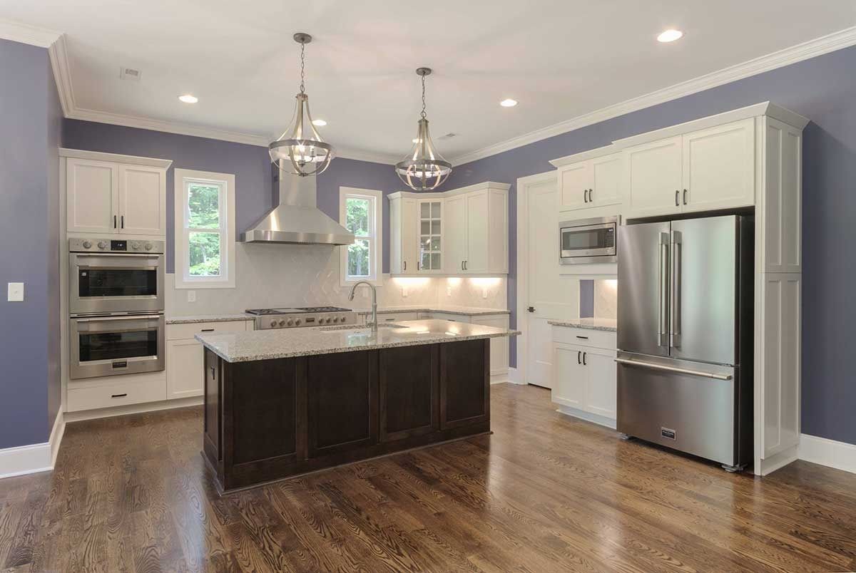 Modern kitchen with white cabinets, dark island, stainless steel appliances, and hardwood floors
