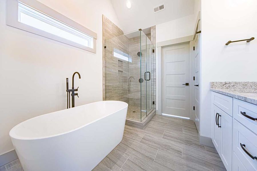 Bright modern bathroom with freestanding tub, glass shower, white door, and light wood-look tile floor