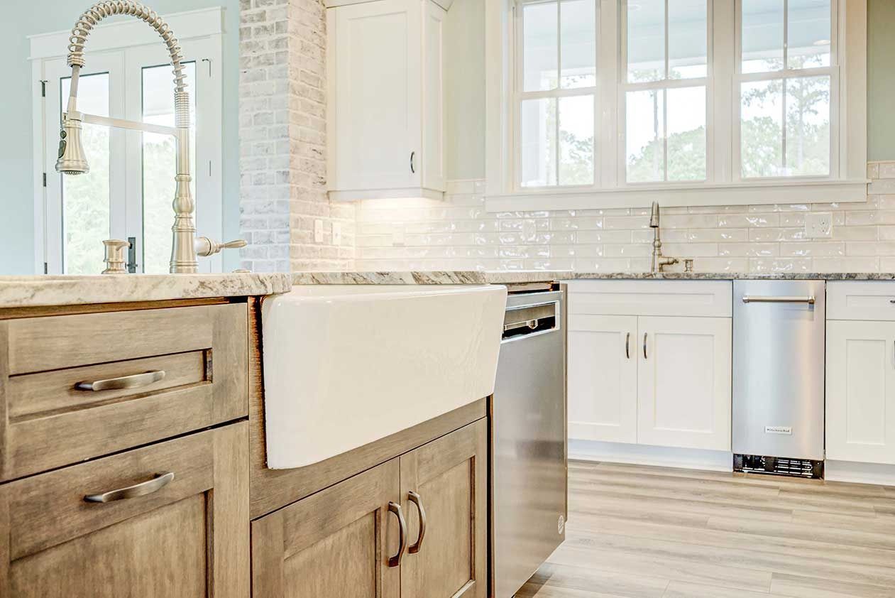 Bright white kitchen with wood island cabinets, farmhouse sink, and large window above the counter