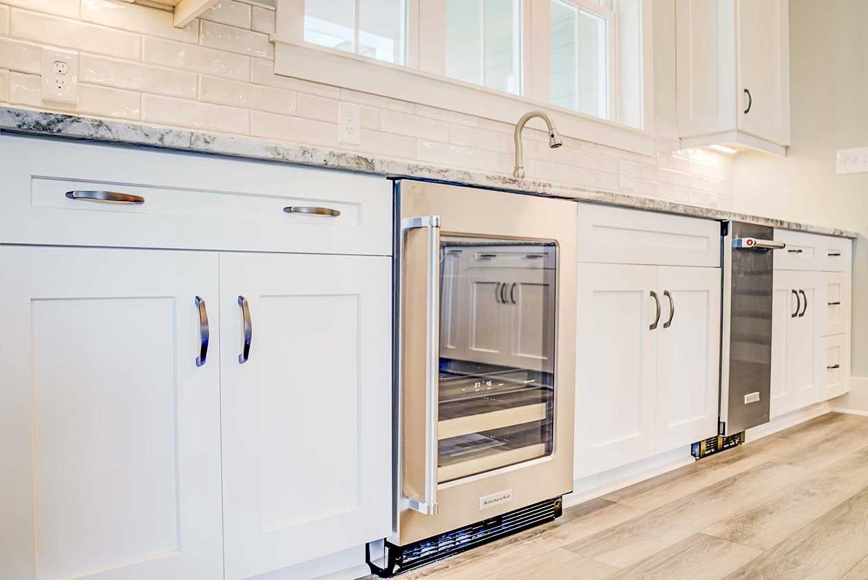 White kitchen cabinets with built-in stainless steel oven and light wood floorboards