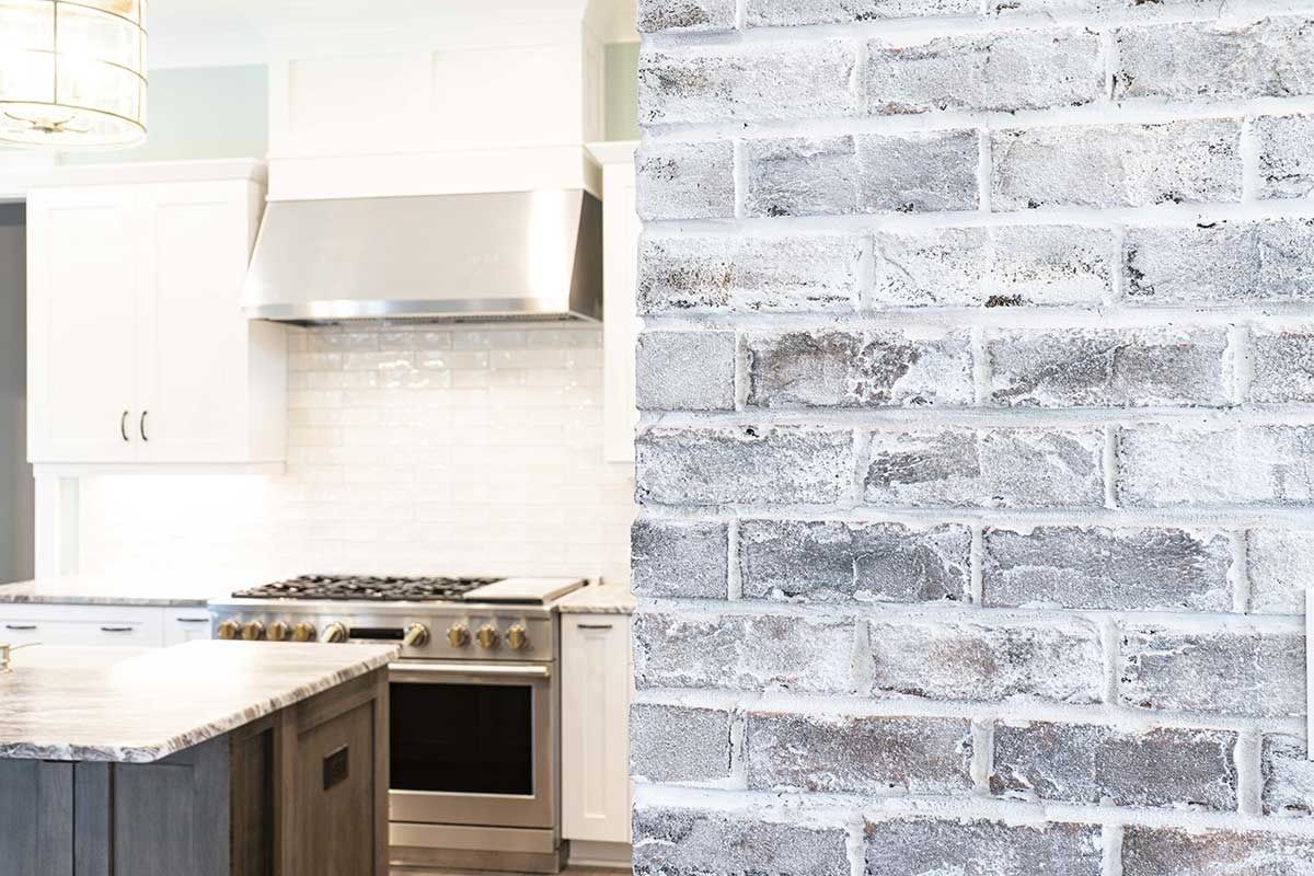 Modern kitchen with white cabinets and a stainless steel stove beside a gray brick accent wall