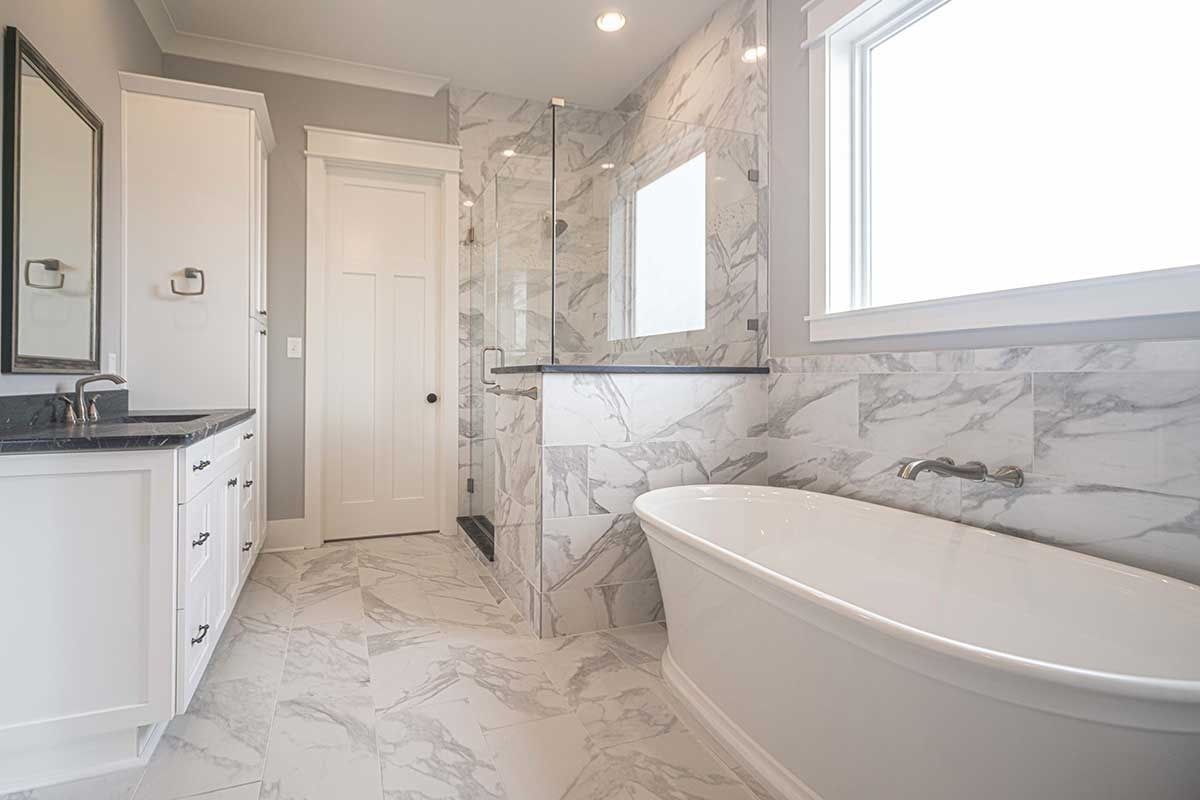Bright white marble bathroom with soaking tub, vanity, and walk-in shower.