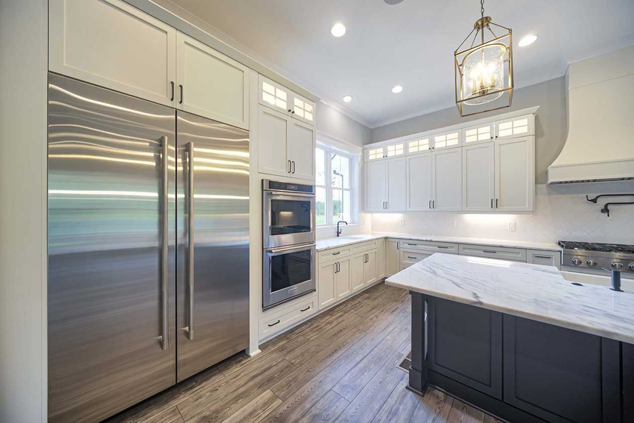 Modern white kitchen with stainless steel appliances, island, and wood flooring