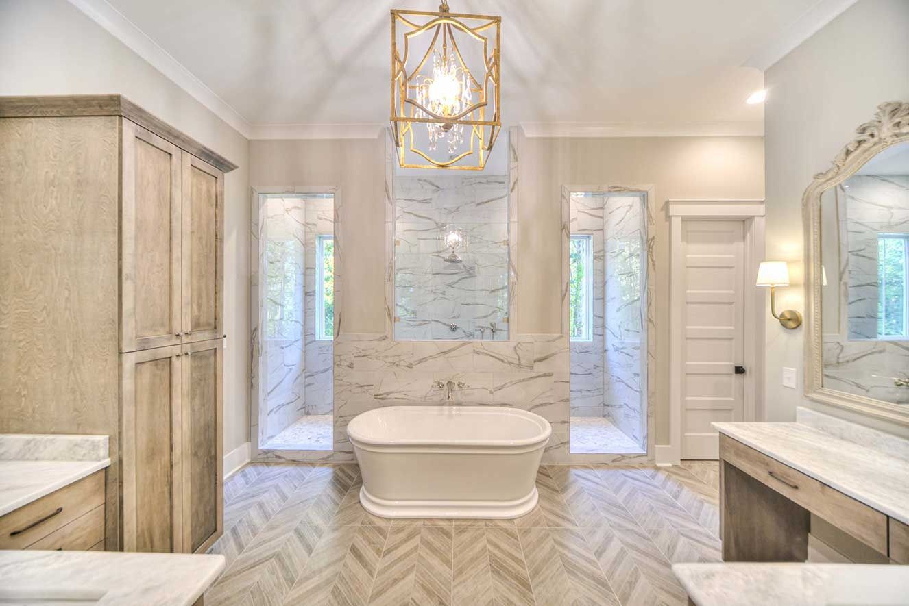 Bright marble bathroom with freestanding tub, gold chandelier, and large mirrors