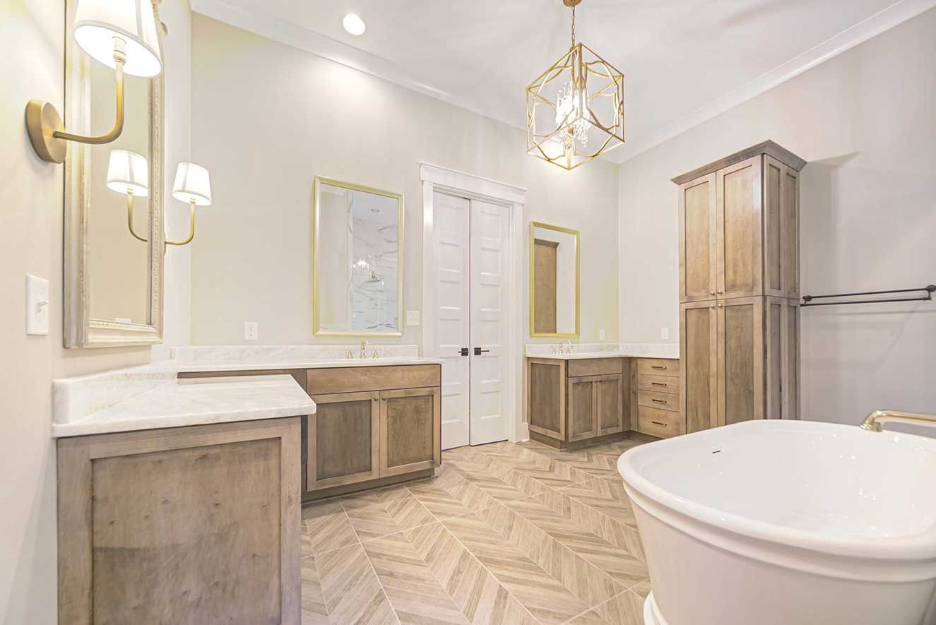 Bright luxury bathroom with double vanity, freestanding tub, wood cabinets, and gold fixtures