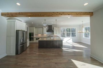 Bright modern kitchen and dining area with wood floors, exposed beam, and large windows