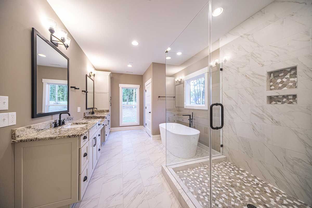 Bright modern bathroom with double vanity, freestanding tub, walk-in shower, and marble finishes.