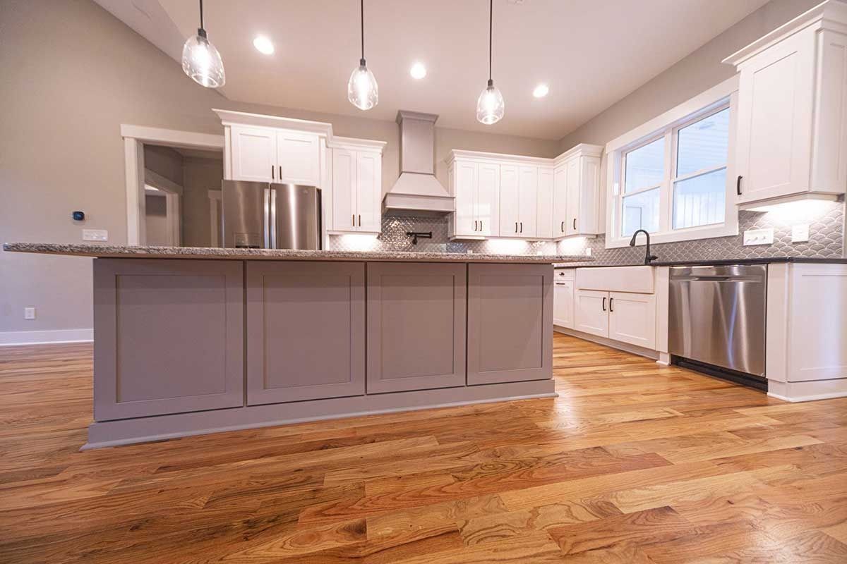 Bright modern kitchen with gray island, stainless appliances, white cabinets, and hardwood floors