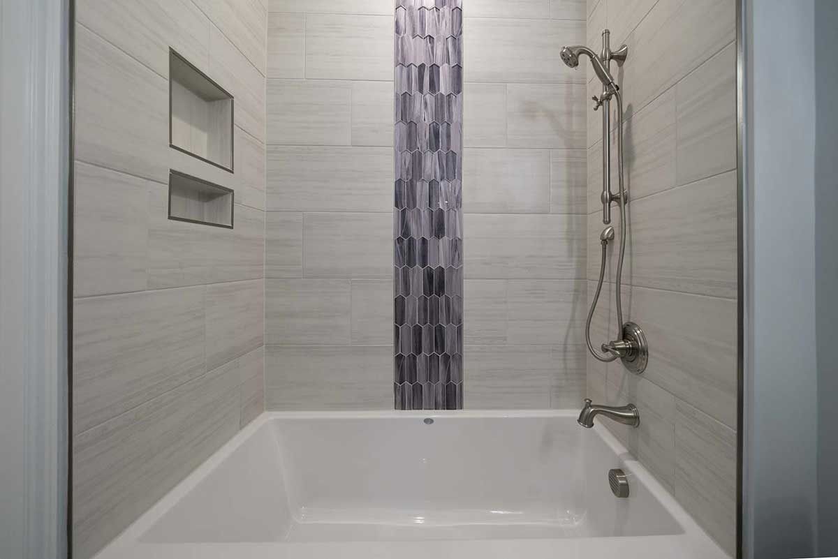 Modern white bathroom with a bathtub, mosaic tile accent, and chrome shower fixture