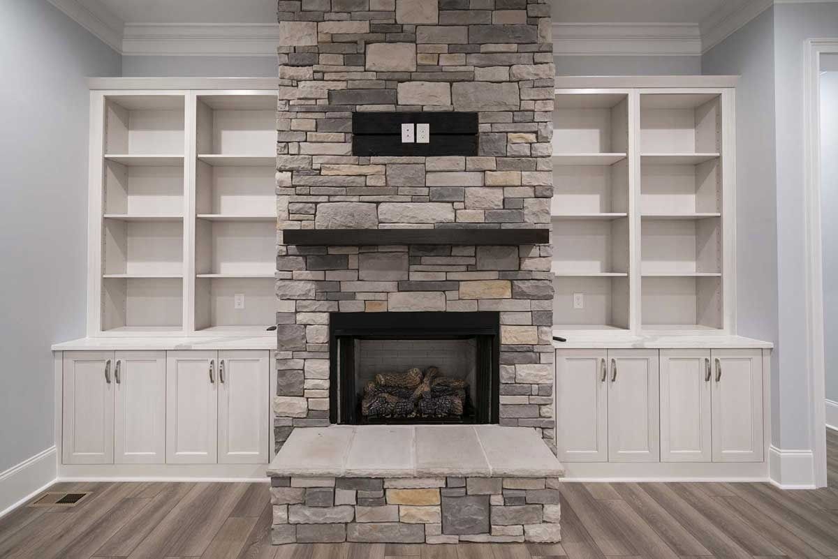Built-in stone fireplace with white cabinets and shelving in a modern living room