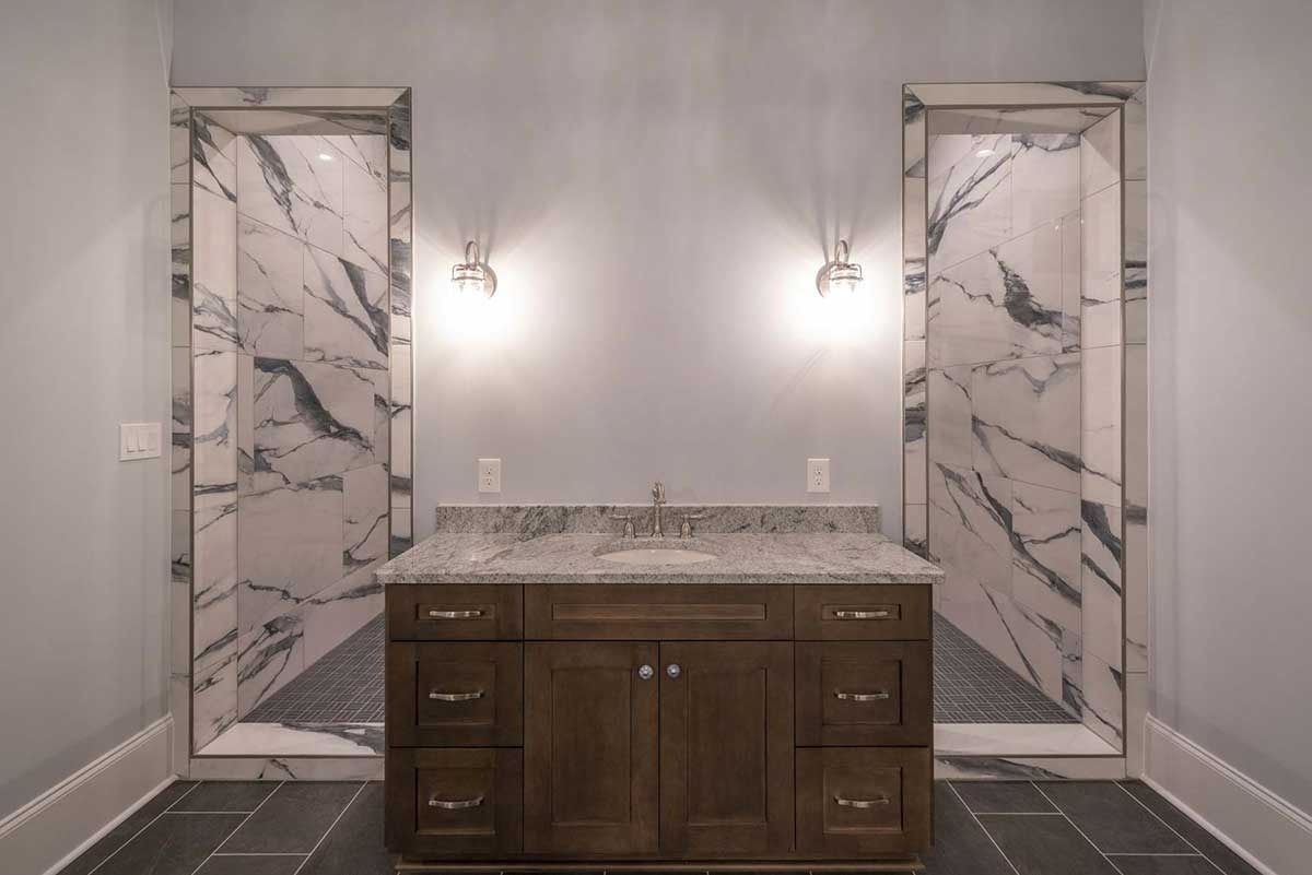 Modern bathroom vanity with marble tile shower surrounds and dark wood cabinet sink.