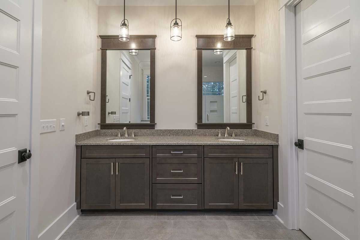 Modern bathroom with double vanity, two mirrors, and white doors on either side