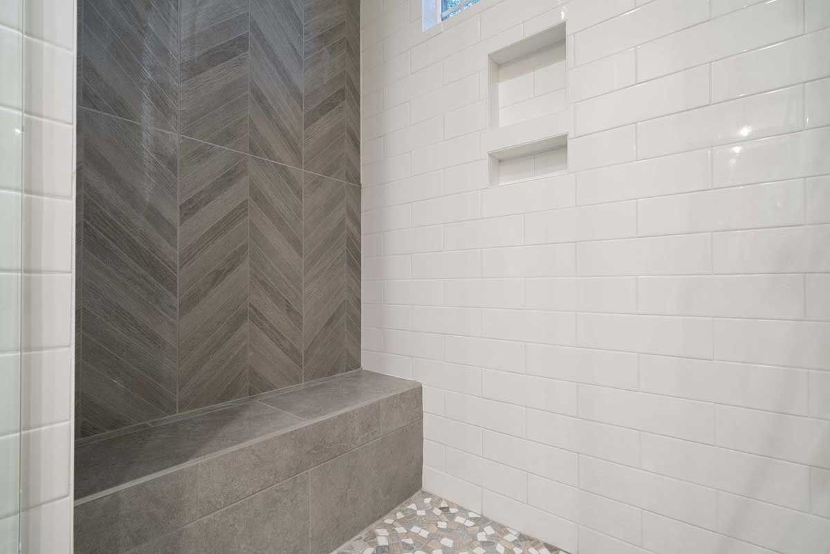 Small tiled shower with gray herringbone accent wall and white subway tiles.