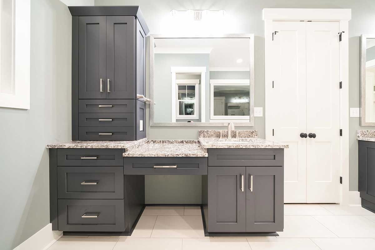 Modern bathroom vanity with dark cabinets, marble countertop, and large mirror, in a bright white room