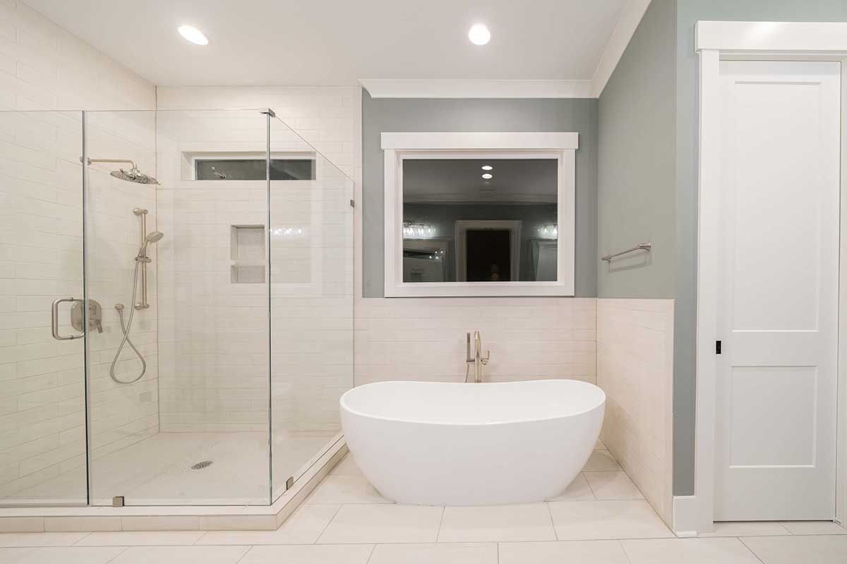 Modern bathroom with glass shower, freestanding tub, and large mirror above a vanity