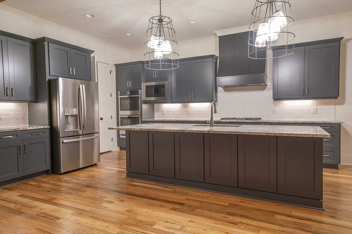 Modern kitchen with dark cabinets, stainless steel appliances, island, and hardwood floors