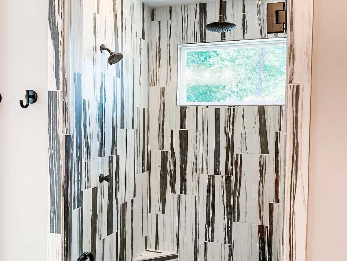 Small bathroom with striped wood-like walls, a showerhead, and a frosted window.